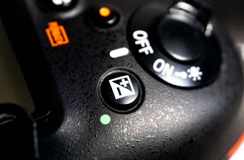 closeup of DSLR camera showing the exposure compensation button.
