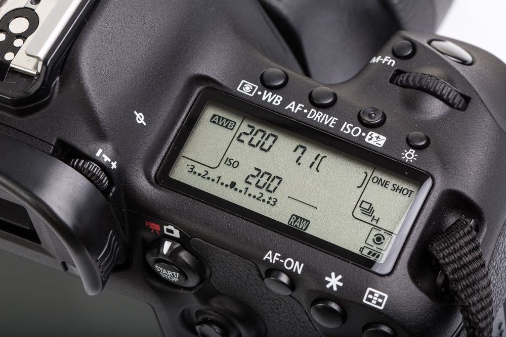 DSLR LCD with settings - shutter speed, aperture, ISO, AF mode.