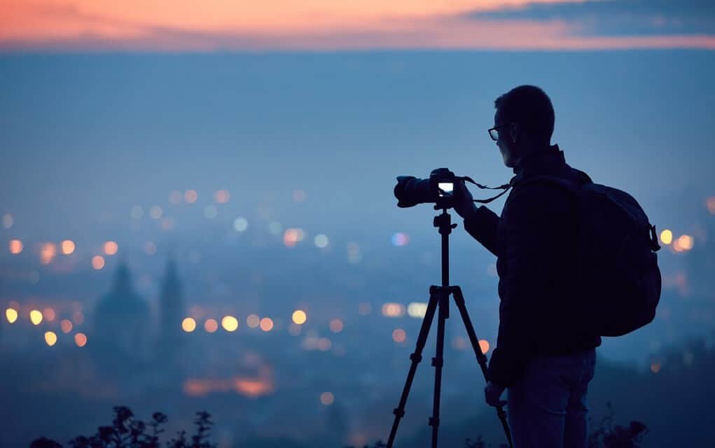 Silhouette of man taking photo on top of a mountain with his DSLR.