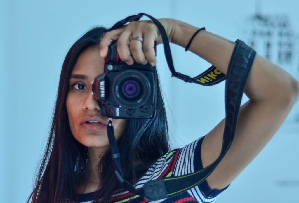 girl taking self-portrait using a Nikon camera in a mirror reflection