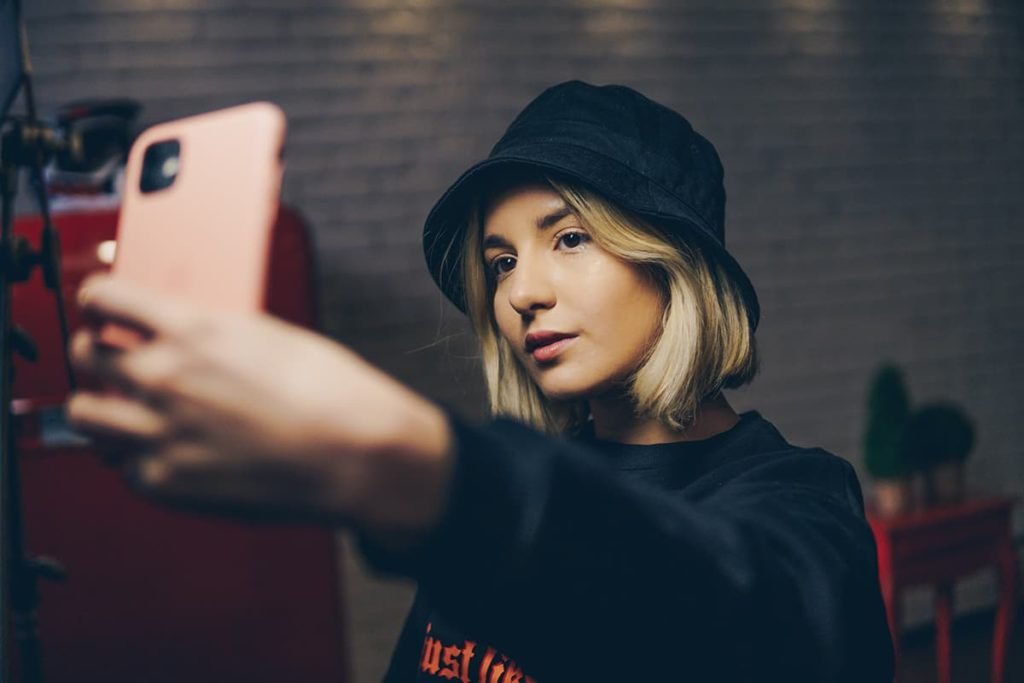 girl taking self-portrait using smartphone camera indoors