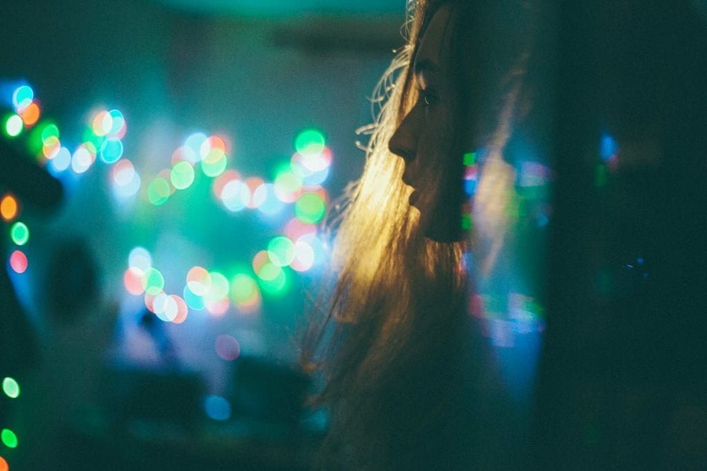 self-portrait of girl in the dark with colourful bokeh in the background