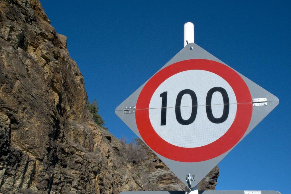 Speed limit sign against a blue sky.