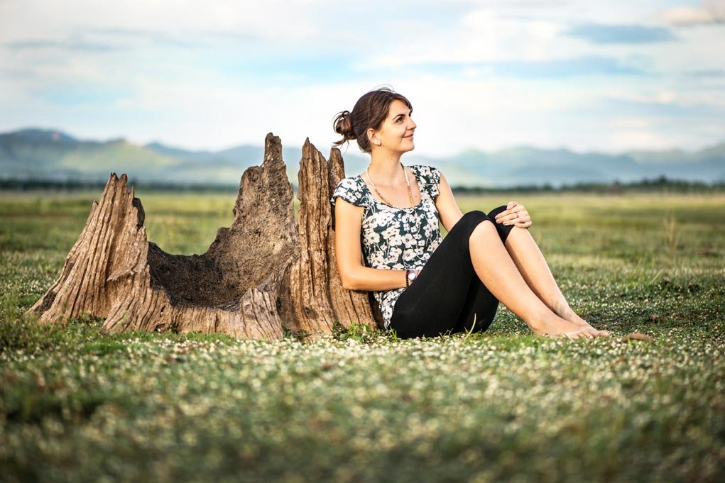woman sitting against an old tree stump for filling the frame.