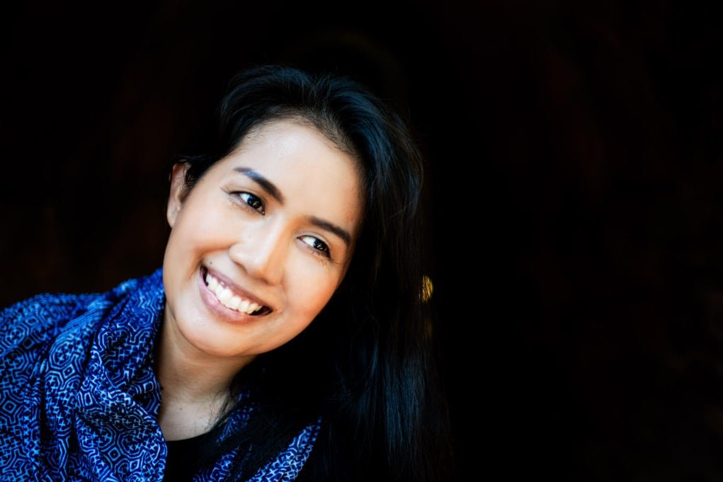 Natural light portrait of a woman with a dark background.