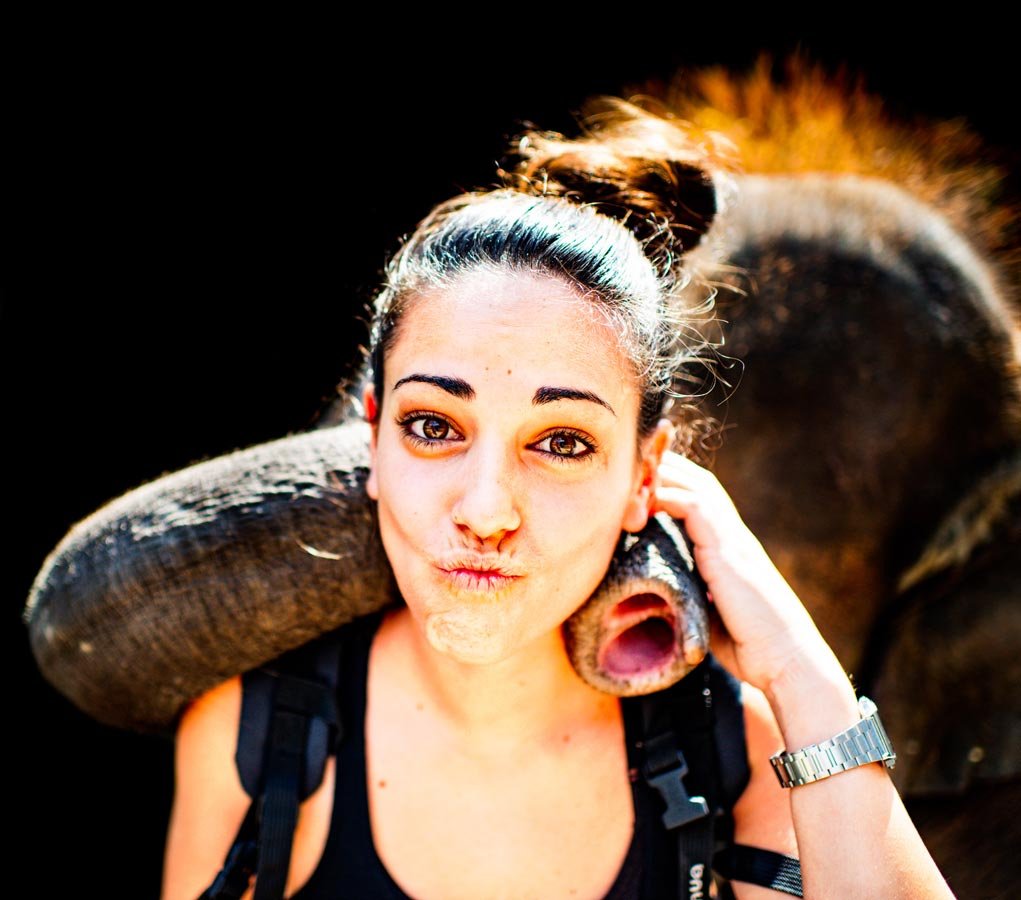 Portrait of a woman with a baby elephant in natural light.