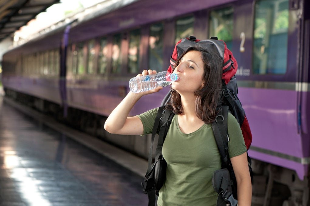 Woman drinking water at the train station.