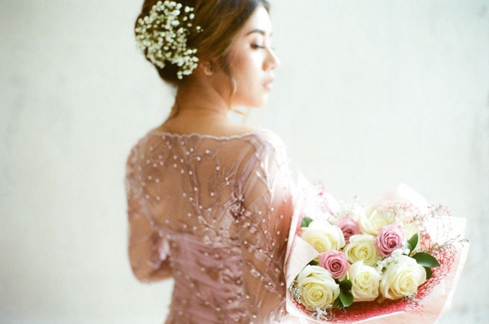 Bride in wedding dress holds flowers for a photo shoot.