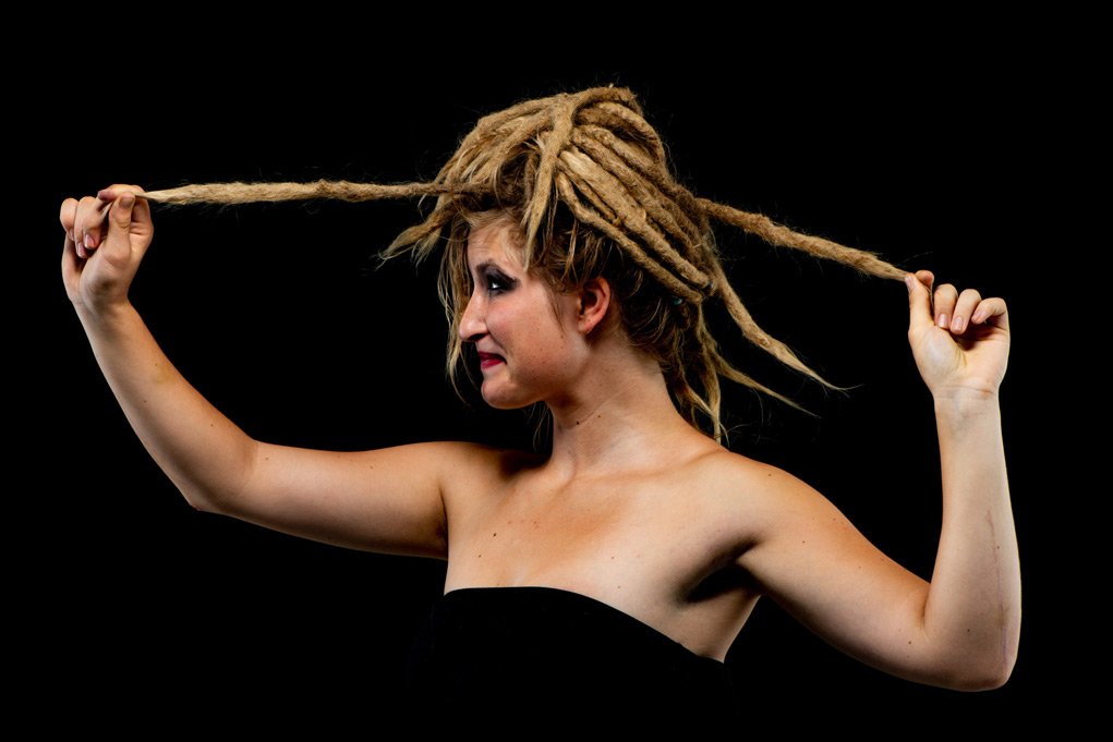 Woman forming a frame with her arms and dreadlocks.