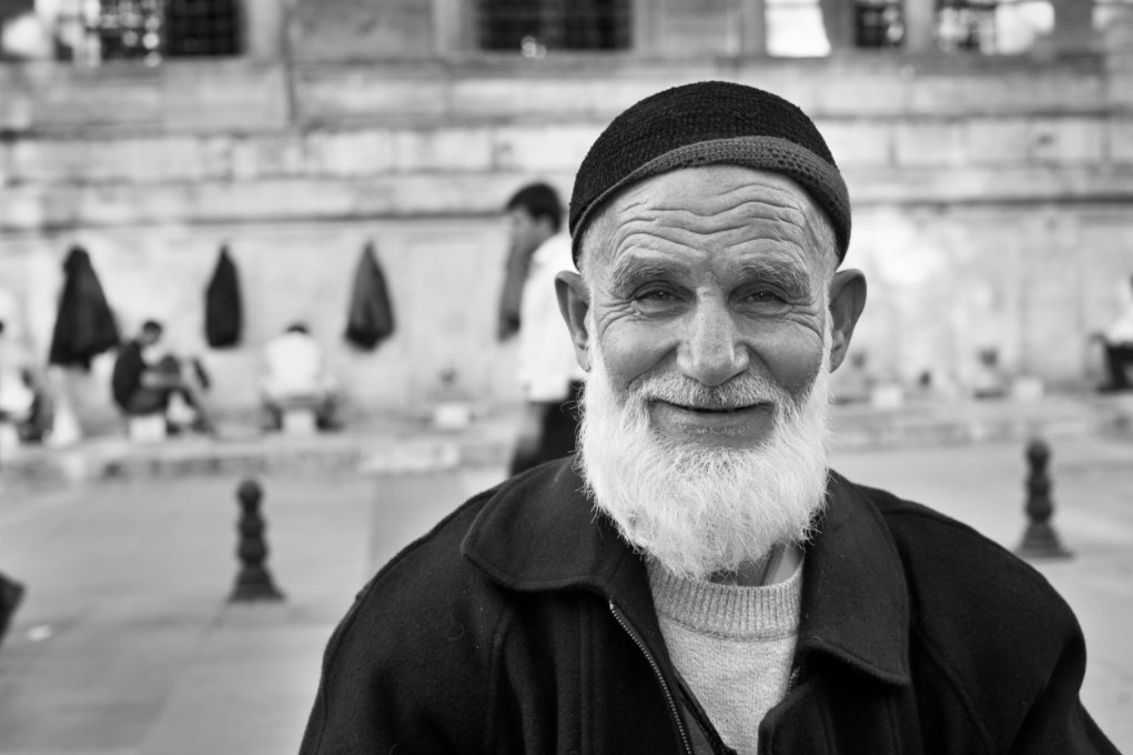 A senior Turkish man with a beard and wearing a cap.