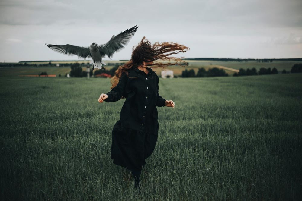 woman running through field with bird.