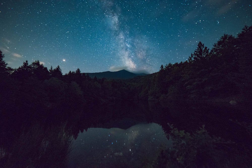 night sky with stars reflecting on water.