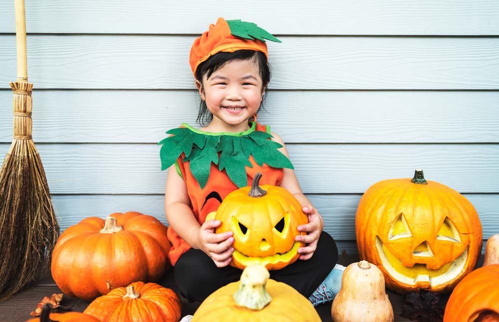 photoshoot of a small kid with jack o lantern pumpkins.