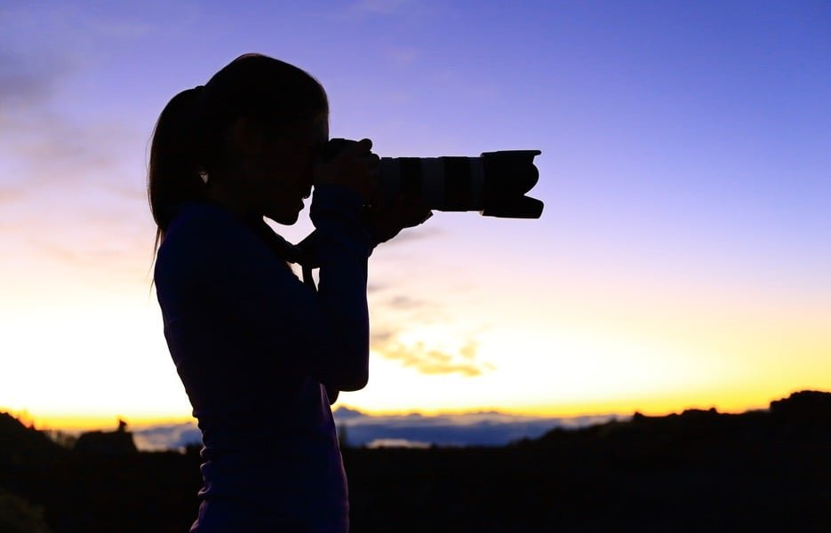 woman taking photos at sunset with best lens for night photography