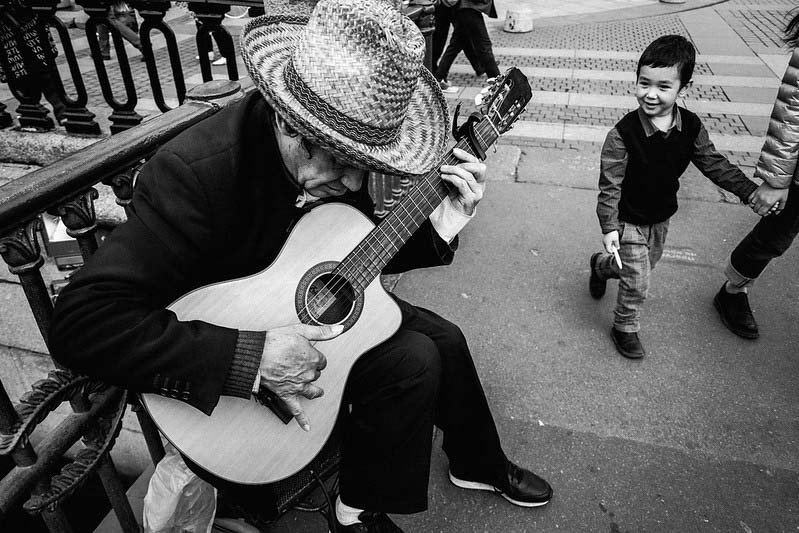 Man holding guitar - street documentary photography in black and white.