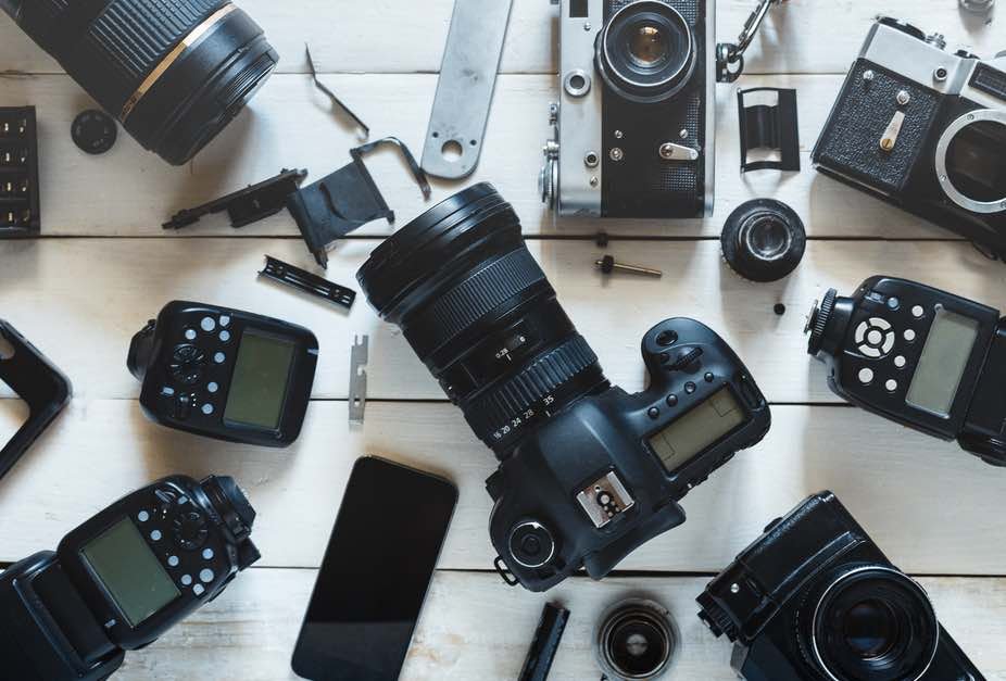 camera equipment on a table including cameras, lenses, and flashes.
