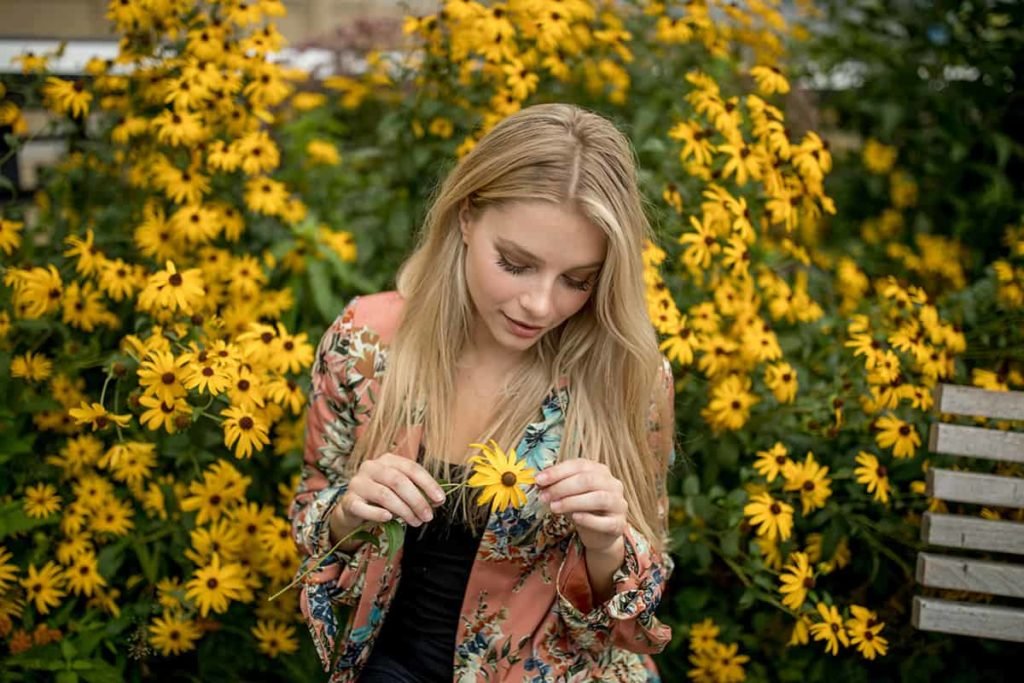 candid image of girl looking at flower.