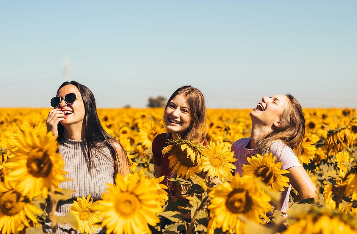 candid portrait of girls laughing in sunflower field.