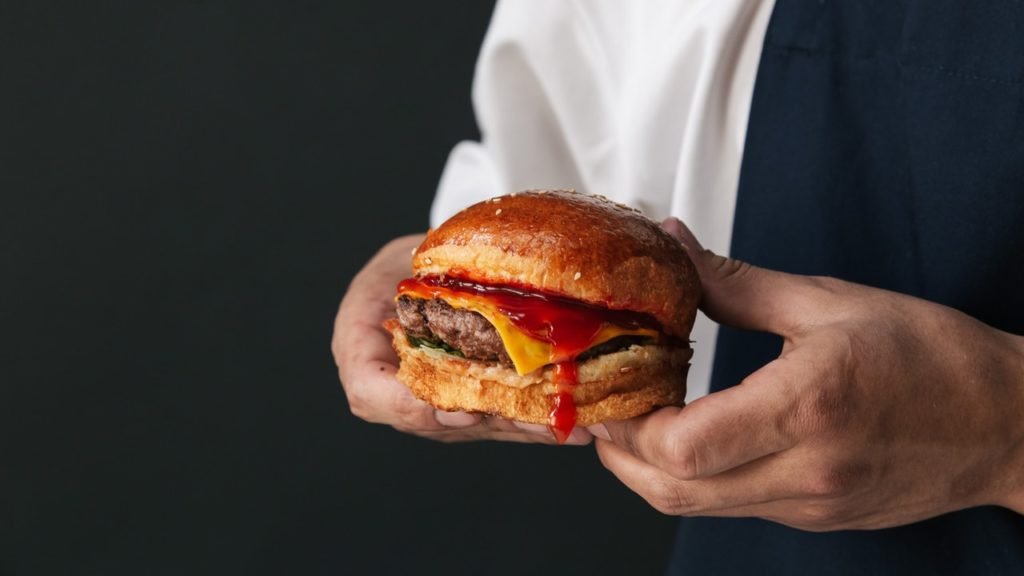 person holding a burger for advertisement.