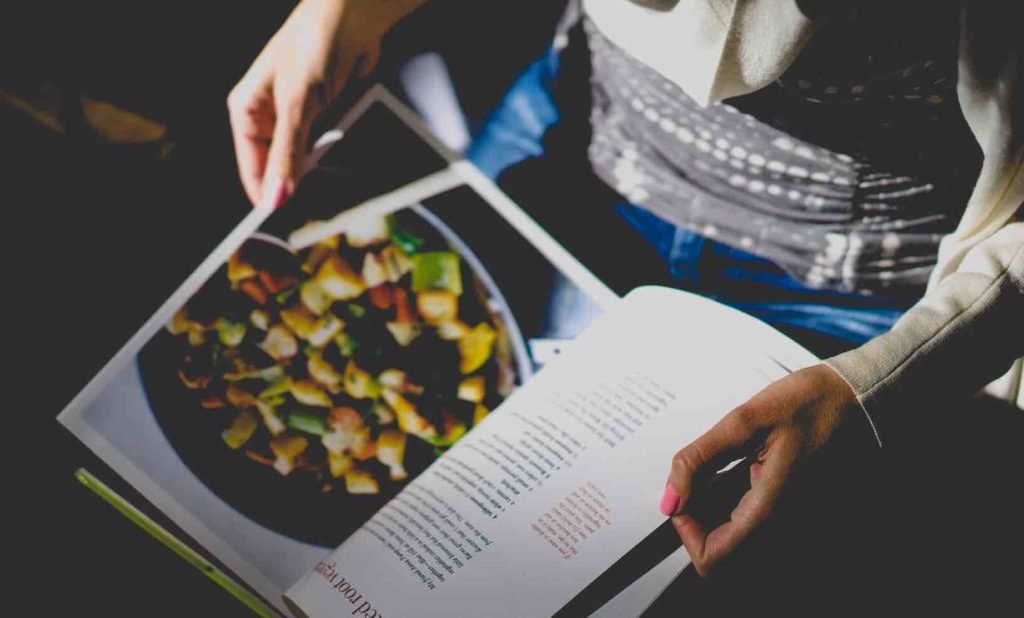 woman holding a cookbook in dark light.