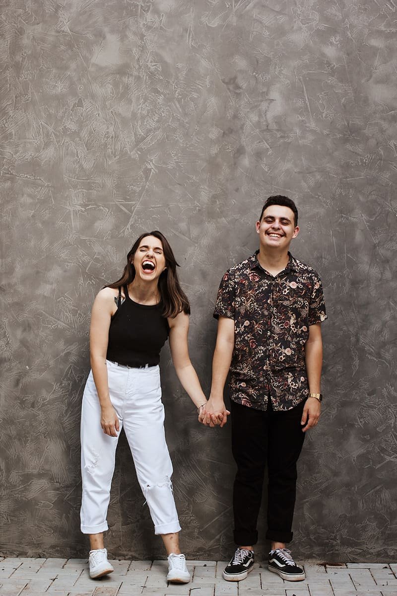 couple poses girl and boy holding hands and laughing