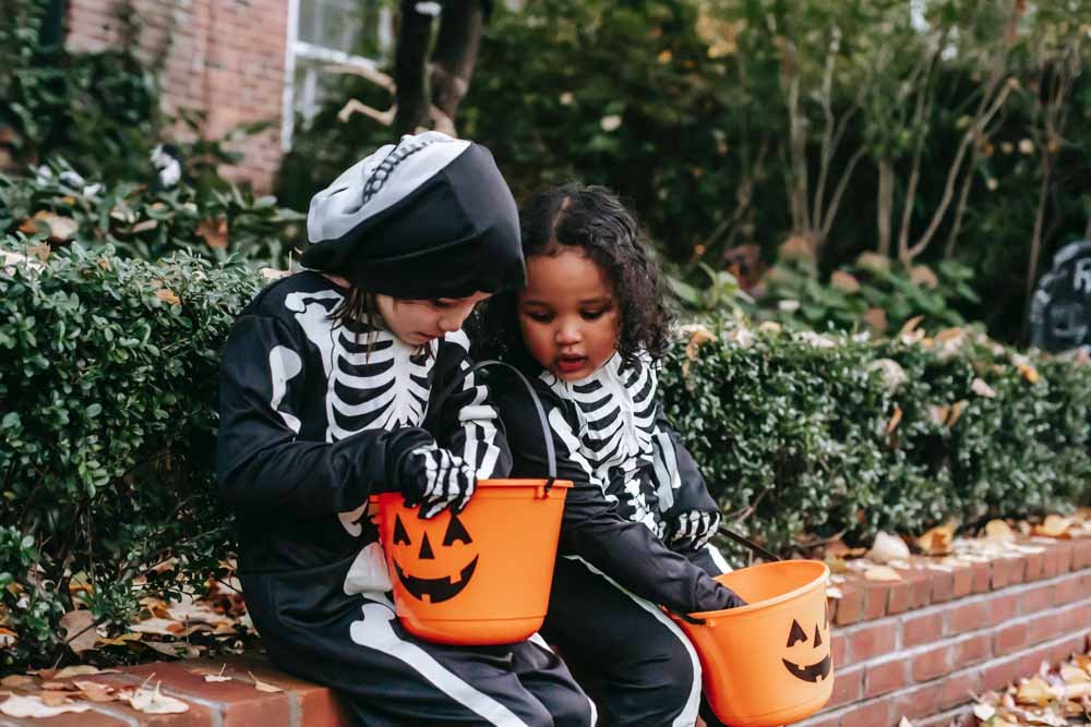 children wearing skeleton printed costumes for Halloween.