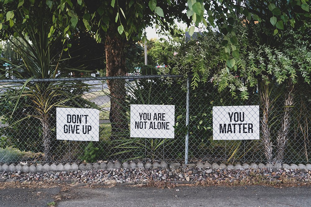 wide shot of a fence with encouraging signs hanging on it.