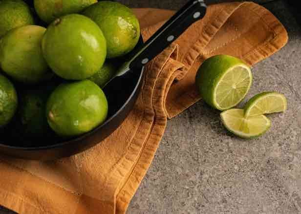 limes styled on black plate with orange linen and knife to demonstrate food photography.