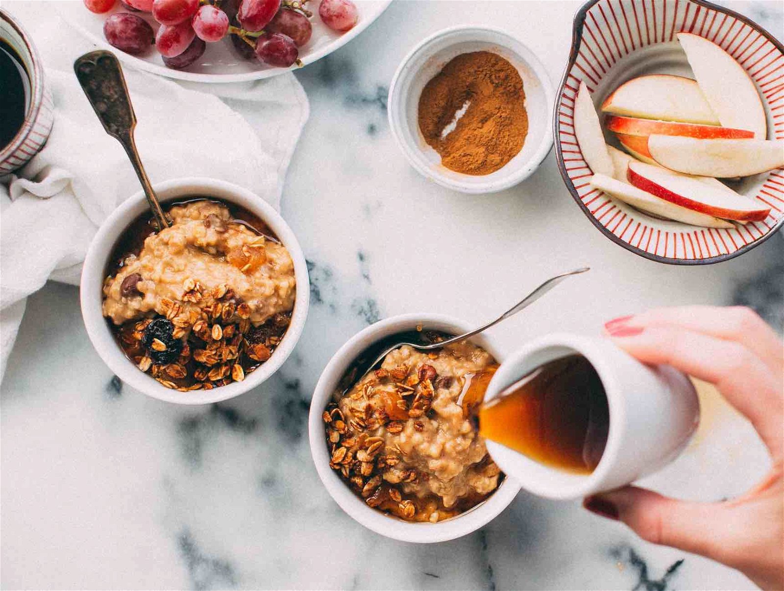 food photography with hand drizzling syrup on oatmeal on marble table.