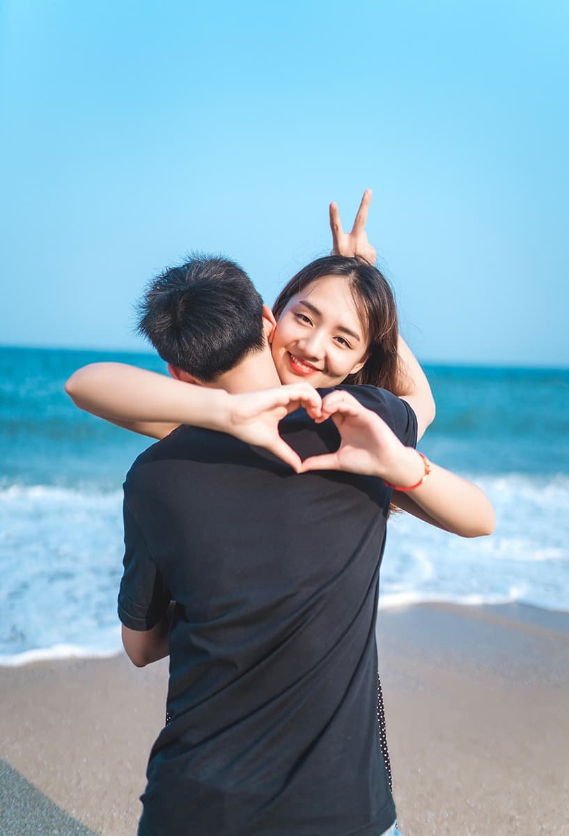 couple making a heart sign on the beach