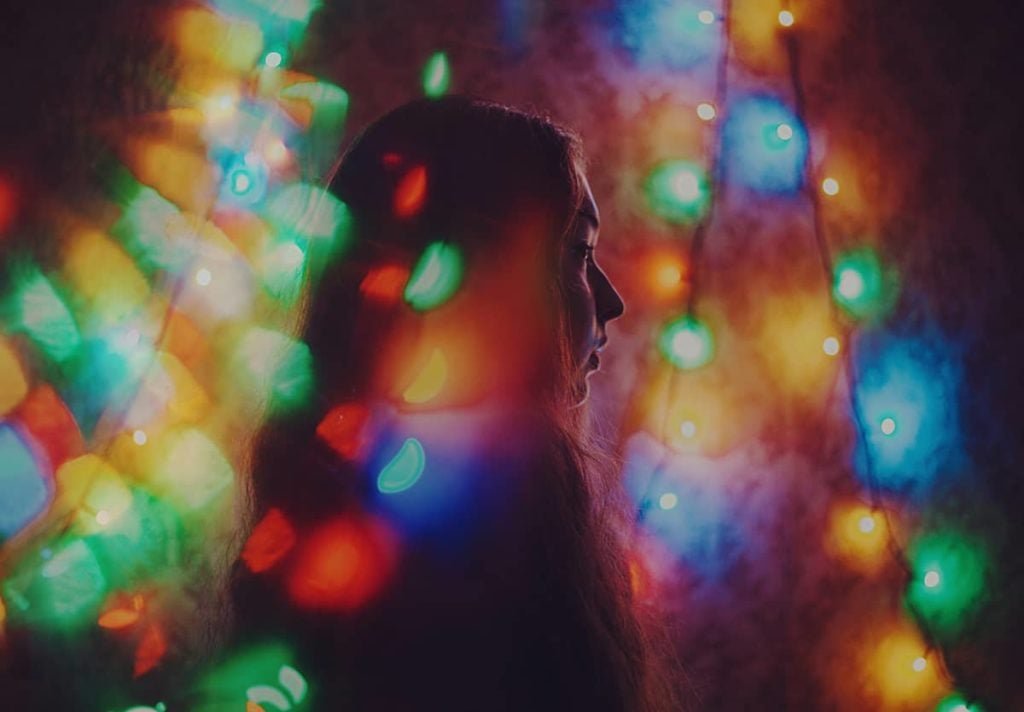 girl surrounded by Christmas lights.