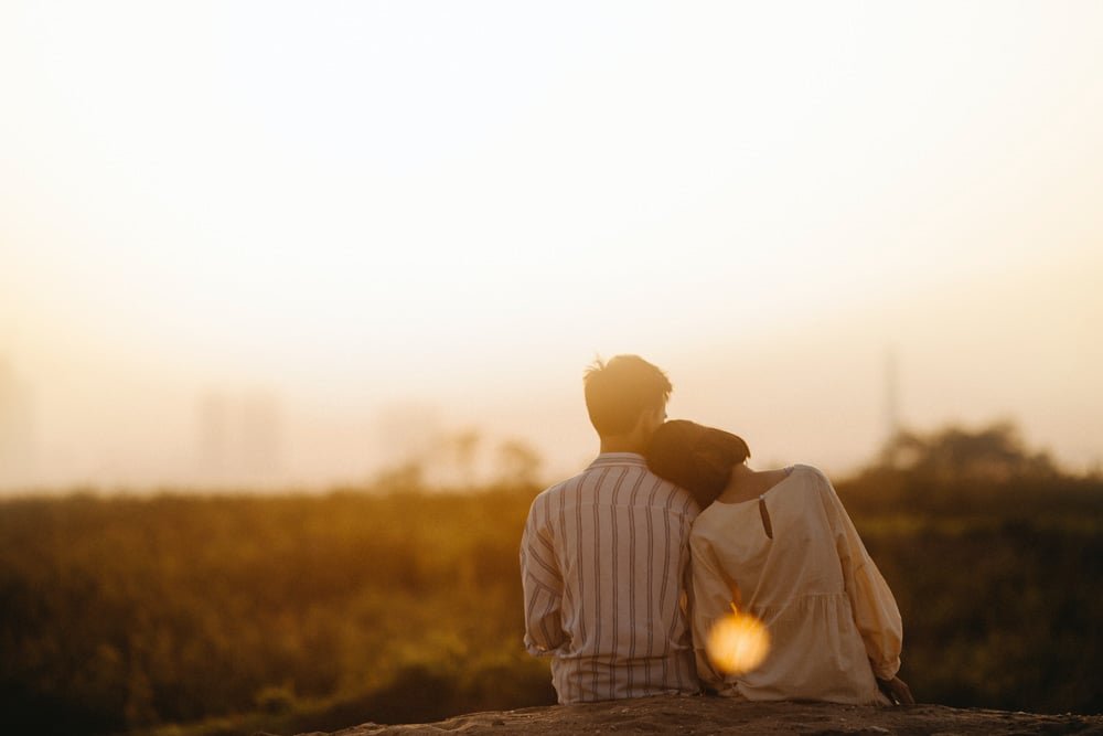 Golden hour photoshoot of couple with lens flare facing away.