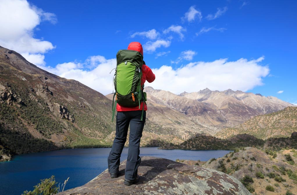 photographer in the mountains taking a light meter reading.