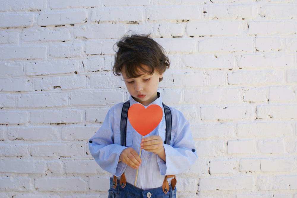 Children holding heart shaped prop for cute photo shoot.