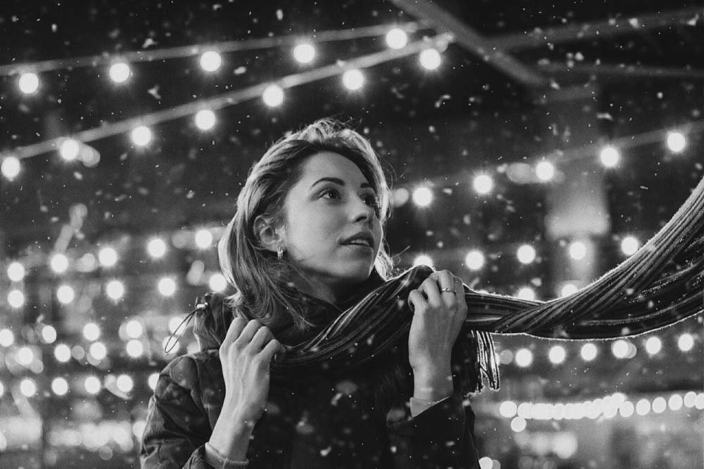 Black and white image of woman with snowflakes falling.
