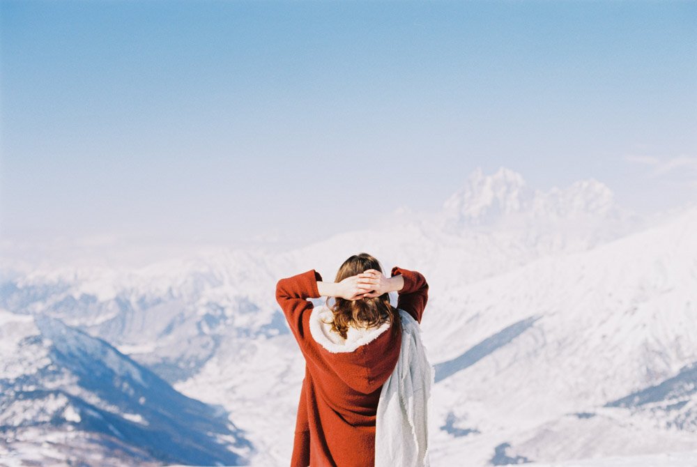 Person standing with a view of snowy mountains.
