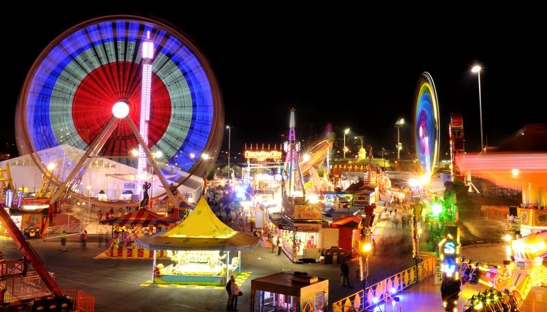 a carnival at night with a moving ferris wheel.