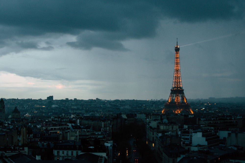 Lights on the Eiffel tower contrast against a dark blue sky. 