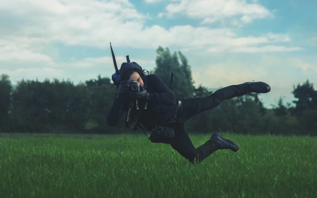 Photographer floating above grass while taking photos outdoors.