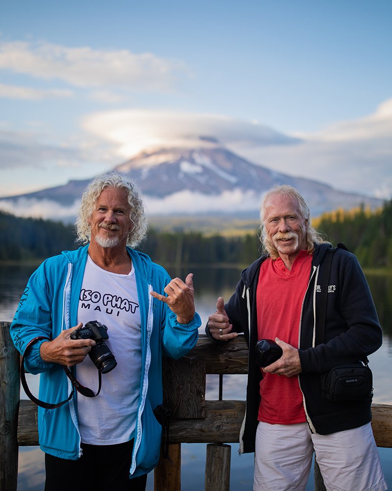 two photographers posing in front of a mountain.
