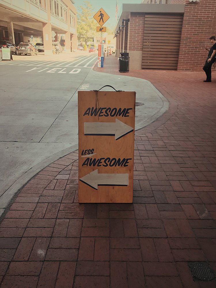 outdoor sign with arrows pointing to 'awesome' and 'not awesome' in different directions.