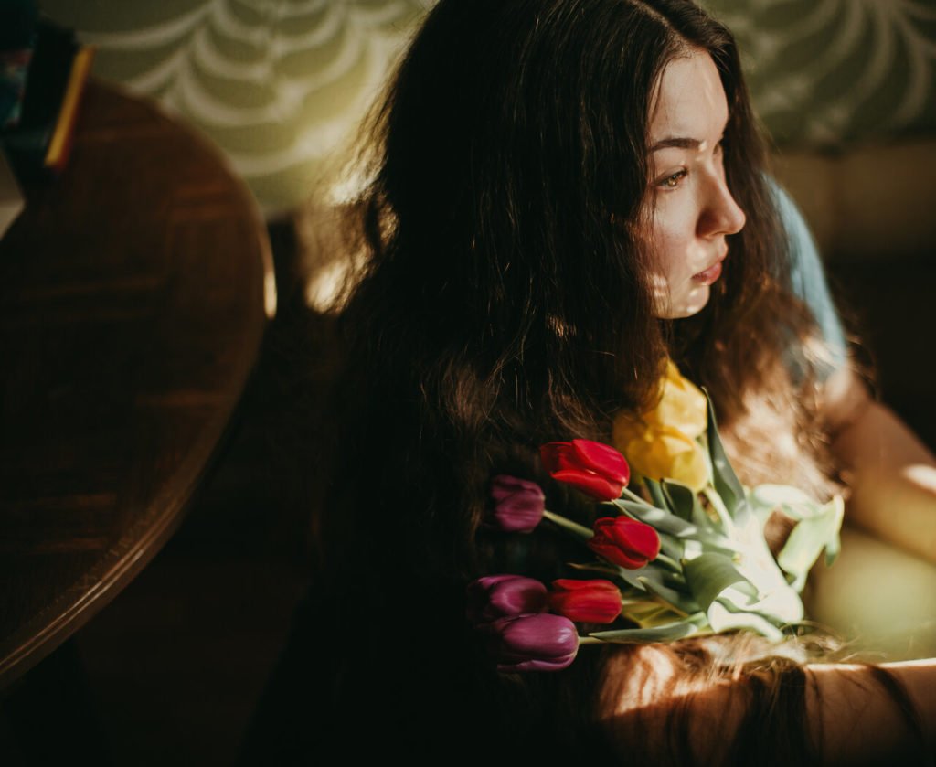 Portrait of girl looking into the distance while holding a bouquet of tulips.
