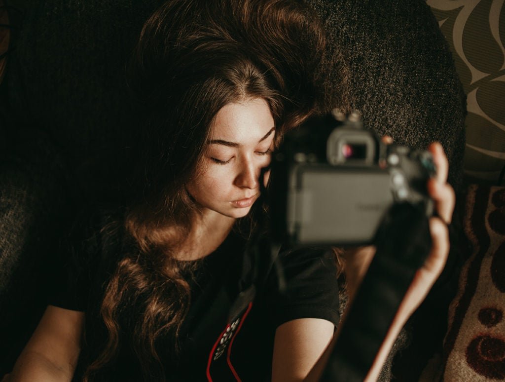 Photo of a girl taking self-portraits indoors.