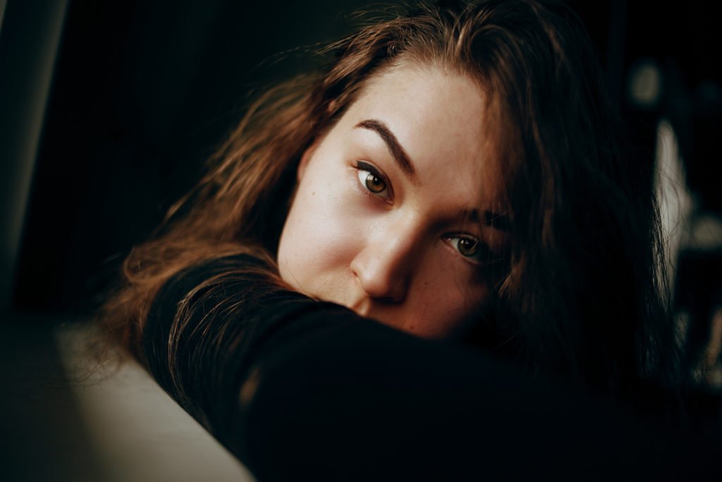 Wide shot of a girl resting on her arm and looking at the camera.