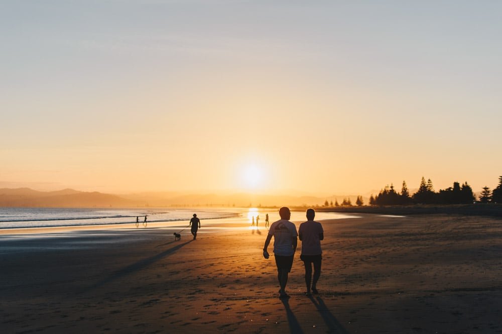 people walking at a beach at sunset time golden hour.