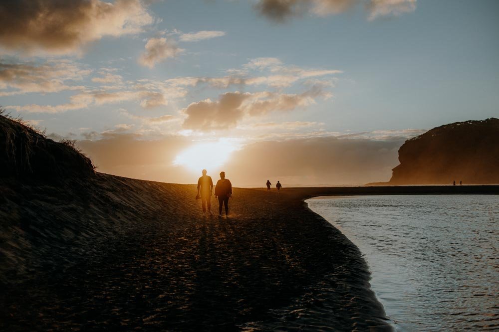 silhouette image of people walking on the beach at sunset.