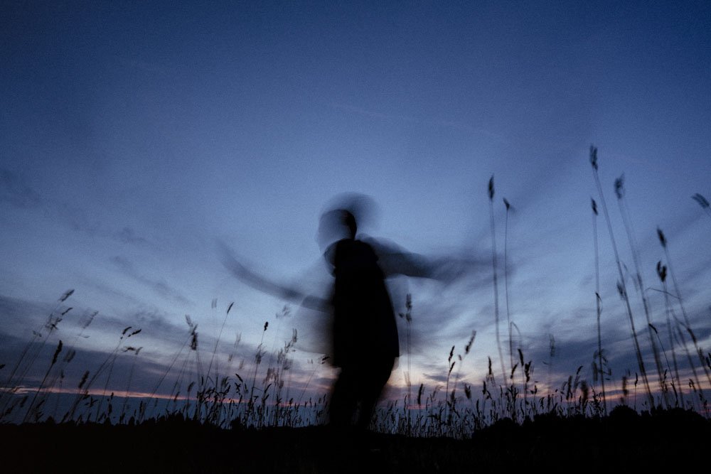 Slow motion, blur image of person in field after sunset.