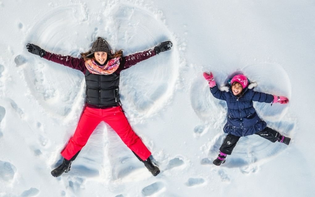 women and kid making snow angels.