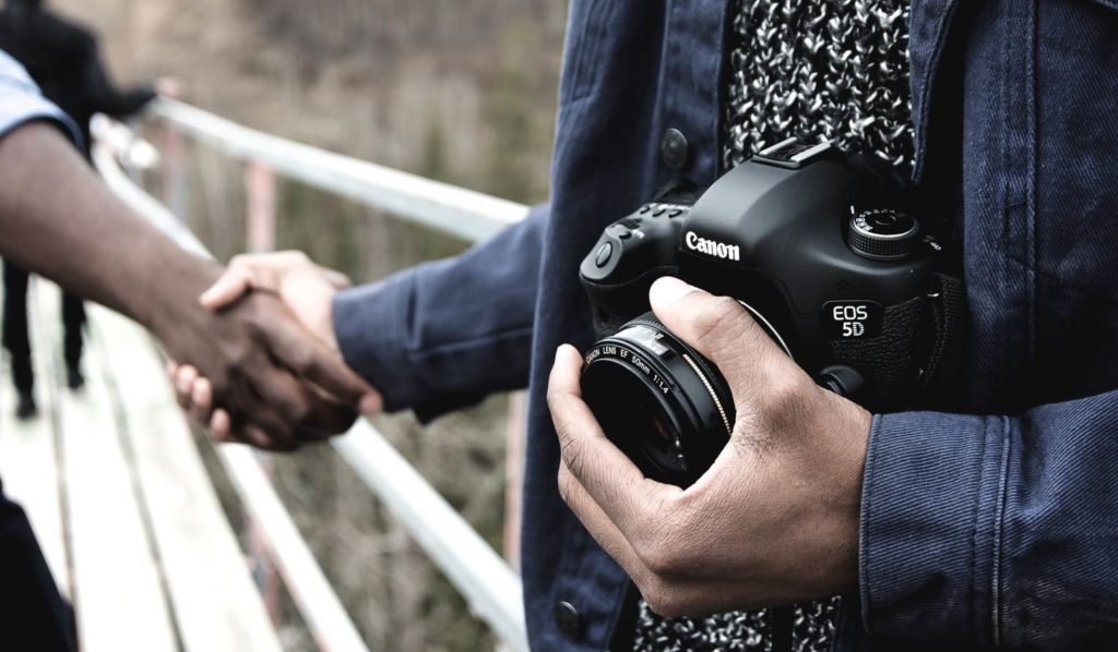 Canon photographer holding hands with a person.