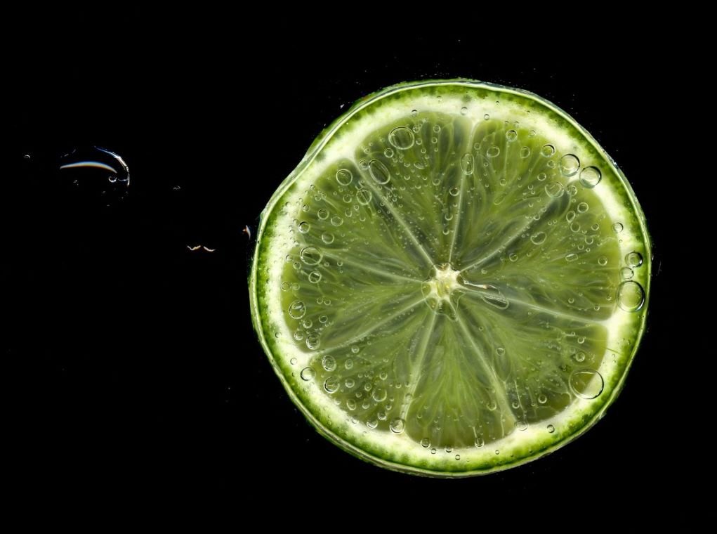 macro photo of lime cut in half against black background.